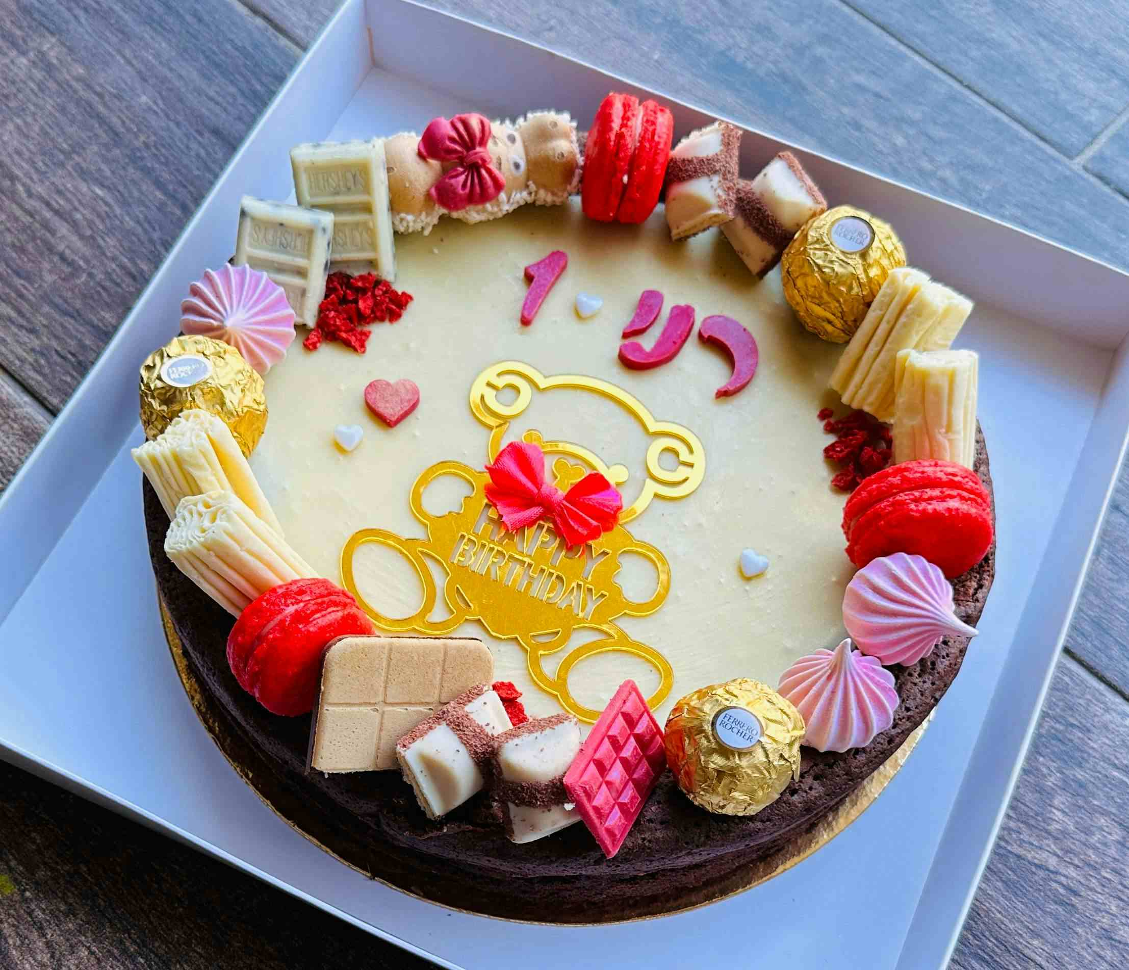   רני חוגגת שנה עם עוגה ורדרדה ושוקולדית  מכוסה בנאש שוקולד לבן ומקרונים אדומים.

